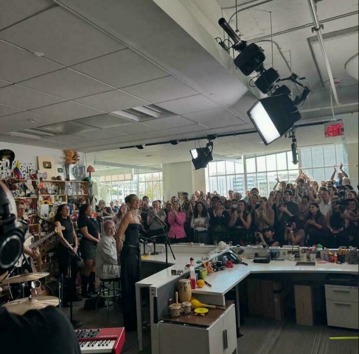 Crowded room with a musician at microphone, fans clapping and recording, showing alternate angles of iconic events in history.
