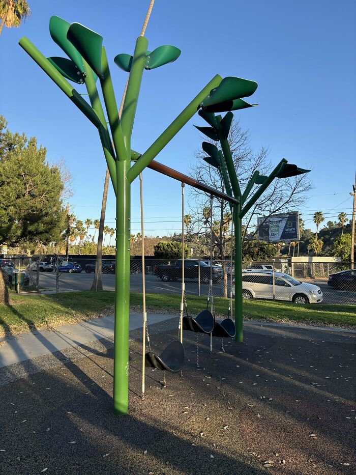 Green playground swings with tree-like metal supports in a park, an example of mystery objects people helped recognize online.