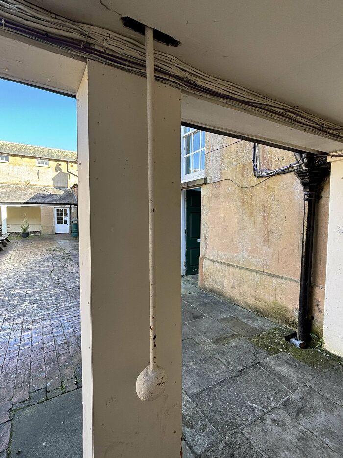 Unrecognized mystery object hanging on a pillar in an old courtyard, part of a collection of mystery objects online group helped identify.