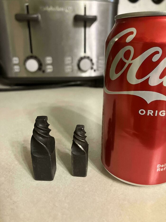 Two small black mystery objects with spiral grooves next to a soda can, featured in an online group for recognizing items.