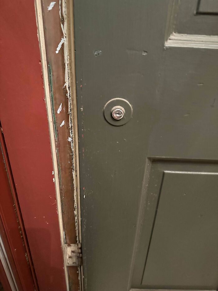 Old green door with a unique round lock mechanism and worn door frame, one of the mystery objects recognized online.