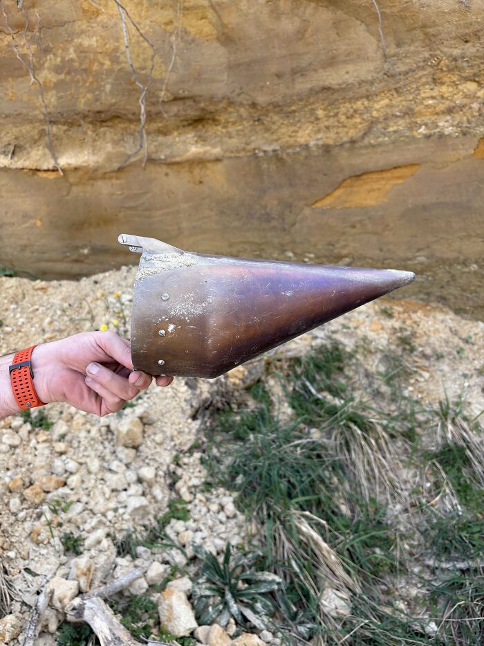 Hand holding a rusty metal cone-shaped mystery object outdoors, part of an online group recognizing unusual items.