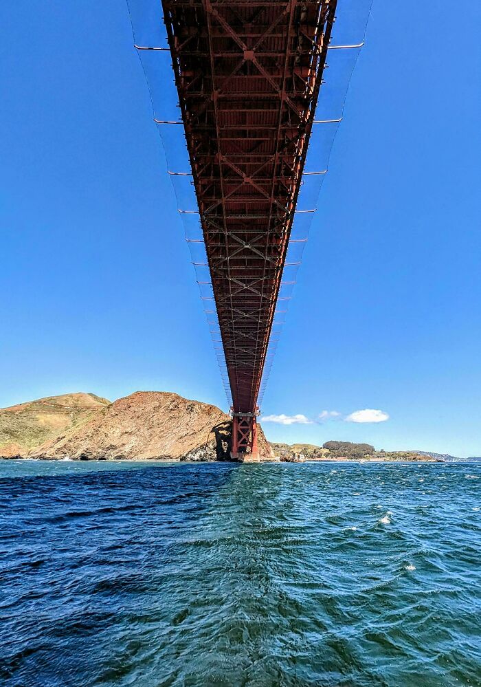 Alternate angle view of an iconic bridge over blue water with hills in the background on a clear day