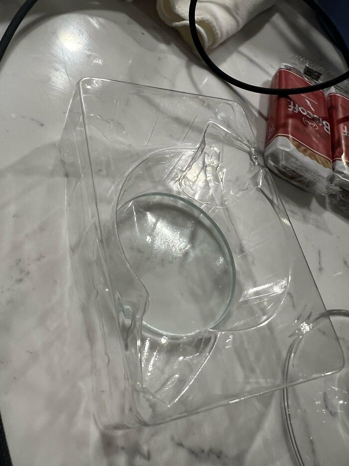 Clear plastic packaging tray with a circular indentation on a marble surface, depicting a mystery object to recognize.