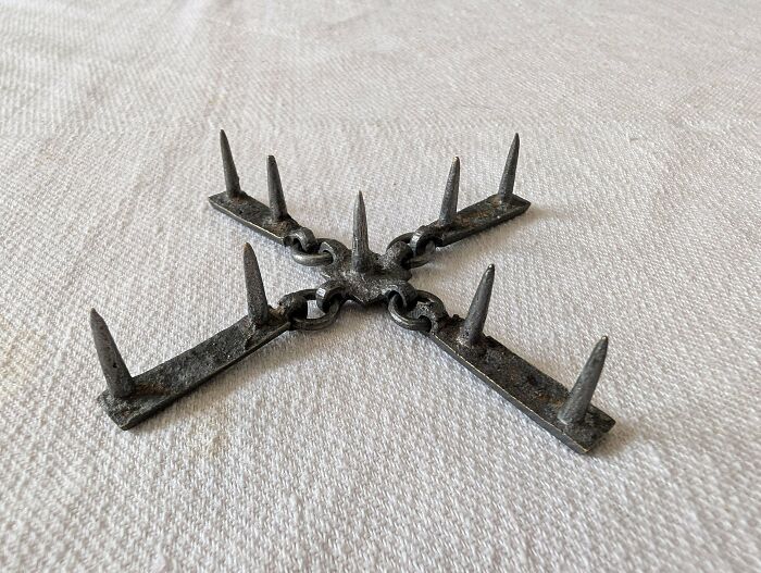 Rusty metal mystery object with spikes linked in a cross shape, featured in an online group recognizing mystery objects.