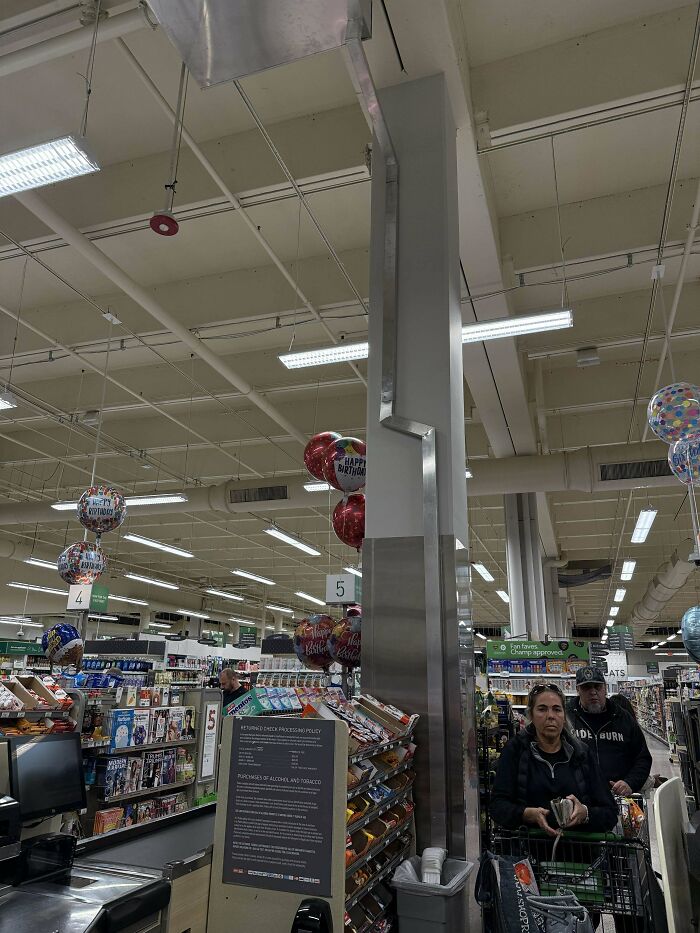Supermarket checkout area with balloons and shoppers, featuring mystery objects recognized by an online group.