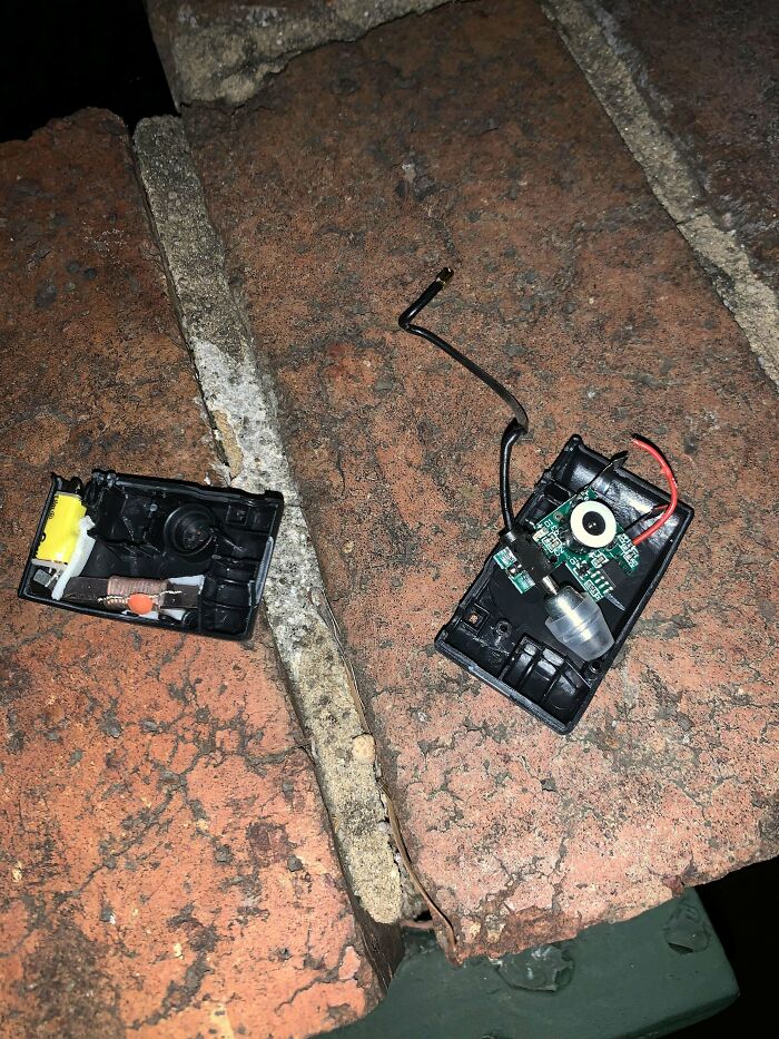 Broken electronic device with exposed circuitry and wires placed on rough brick surface, mystery objects recognized online.