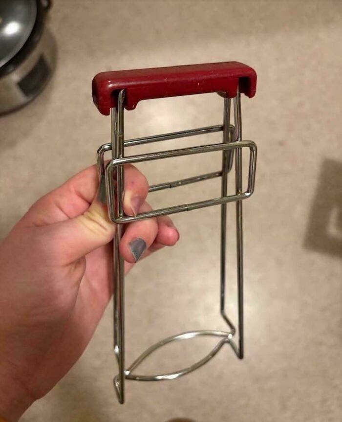 Hand holding a mystery object with a red handle and metal frame, from an online group helping recognize mystery objects.