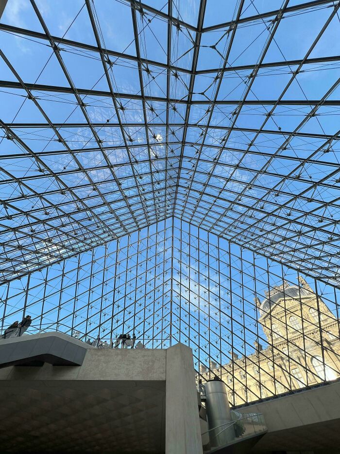 Glass ceiling structure with blue sky and historic building visible through alternate angles in iconic places of history.