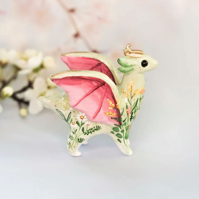 Adorable pocket-sized animal figurine by Vallavica, featuring pink wings and floral details.