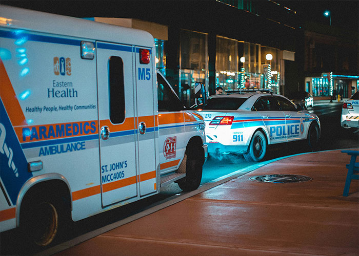 Ambulance and police car with flashing lights at night, illustrating HOA-related emergency response.