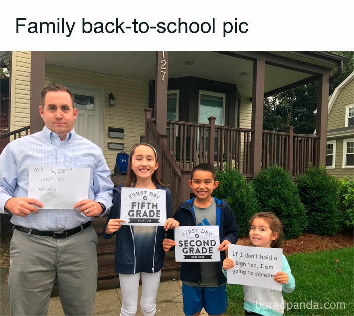 Dad holds "6,287th day of work" sign with kids in back-to-school photo, showcasing relatable parenting humor.