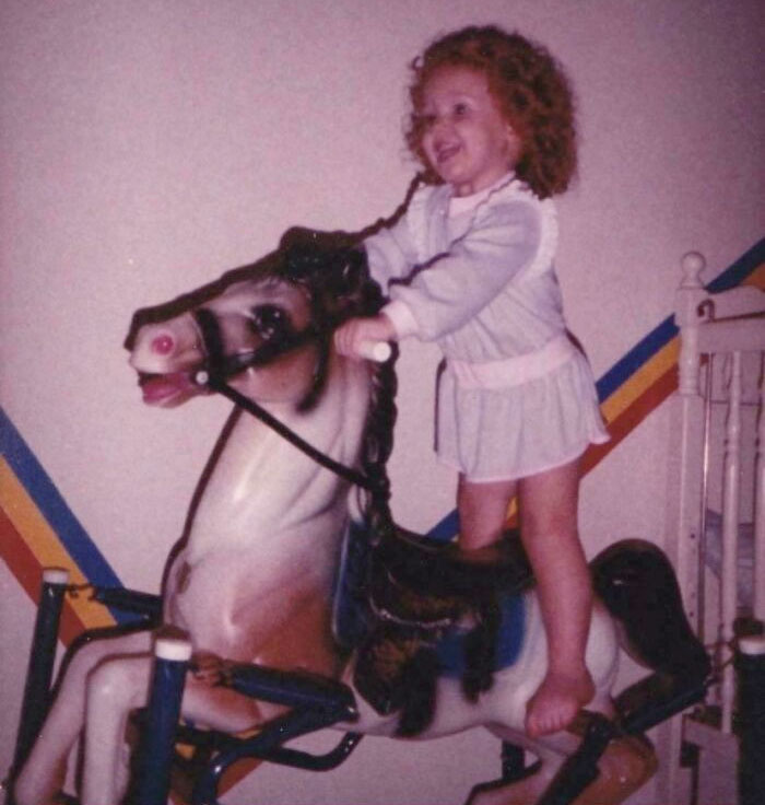 Child on vintage rocking horse, evoking nostalgic feelings.