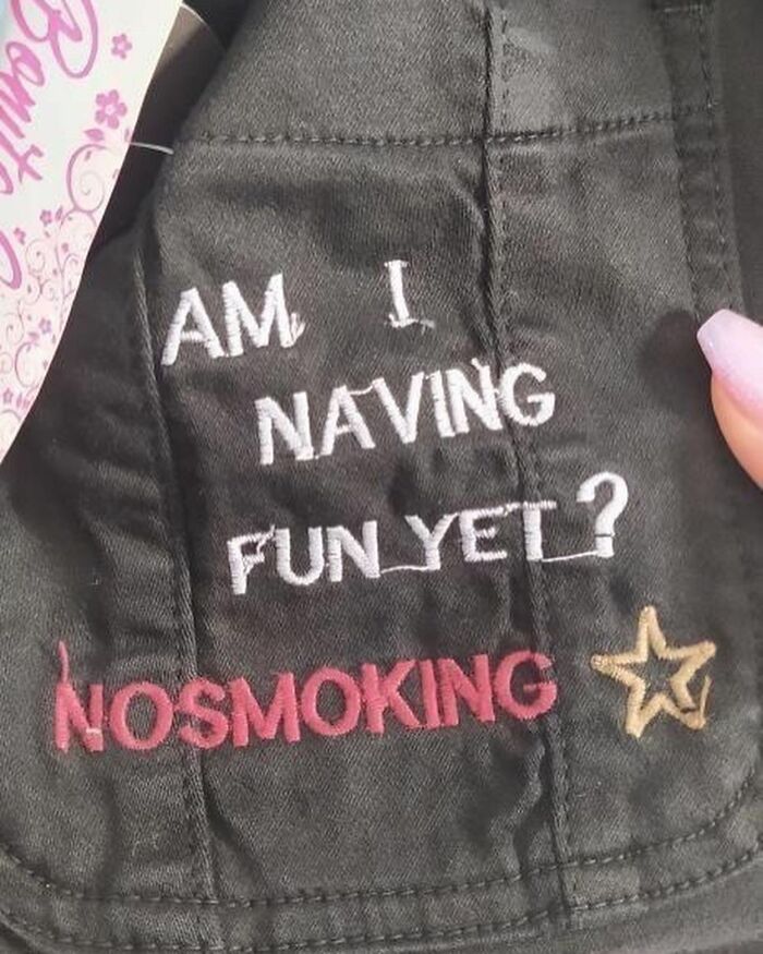 T-shirt with funny mistranslation: "AM I NAVING FUN YET? NOSMOKING" in bold text.