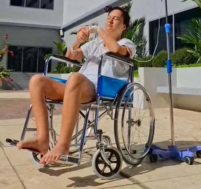 Woman in wheelchair with IV drip, outdoors.