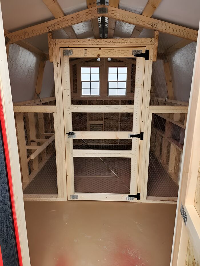 Woodworking ideas shown in a spacious wooden coop with framed door and wire mesh panels inside a building.
