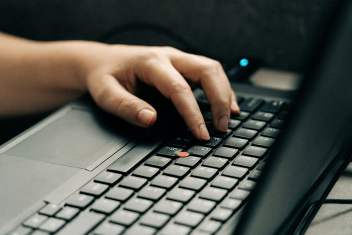 A person typing on a laptop keyboard, illustrating SEO deliverables creation in a focused work environment.
