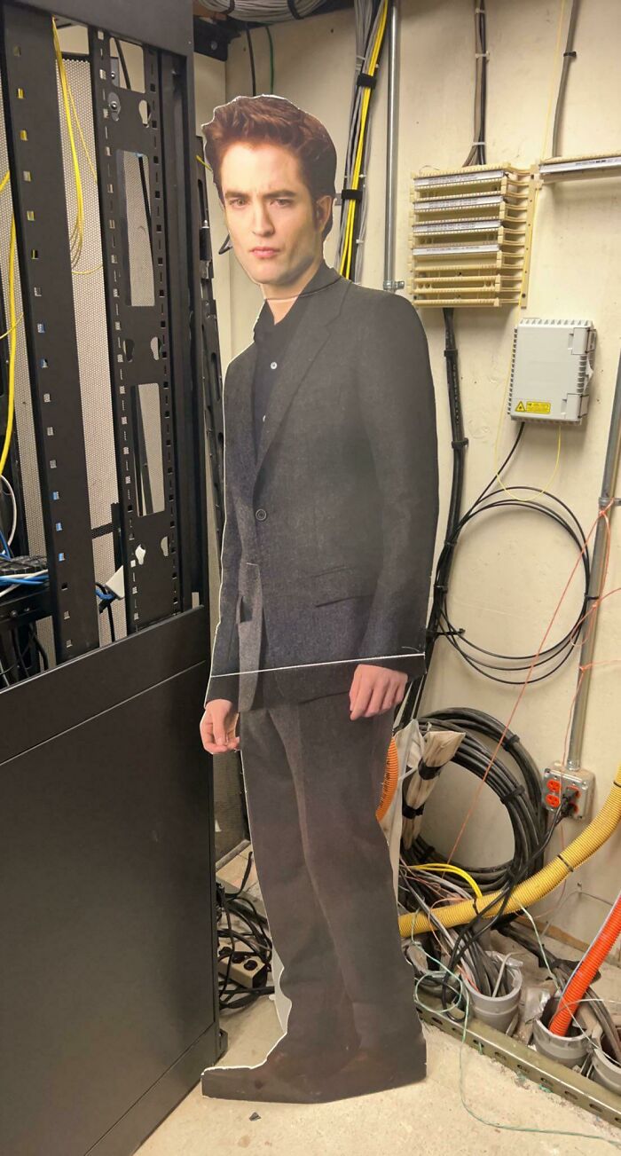 Cardboard figure in a dimly lit room, surrounded by wires. Weird and creepy house decor spotted unexpectedly.