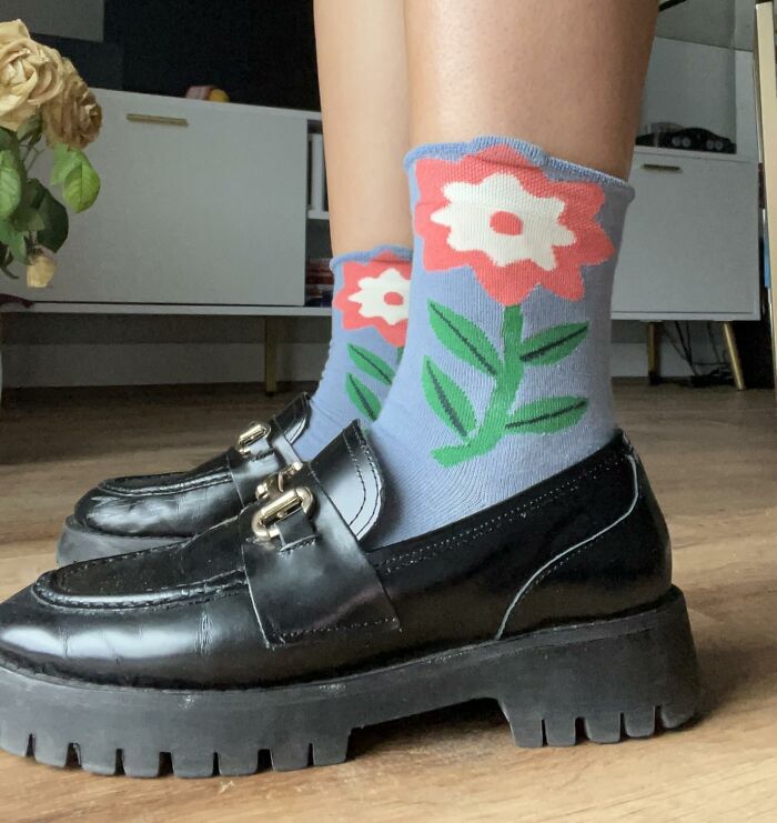 Legs wearing flower-patterned socks paired with chunky black loafers, showcasing playful items to unleash your inner child.