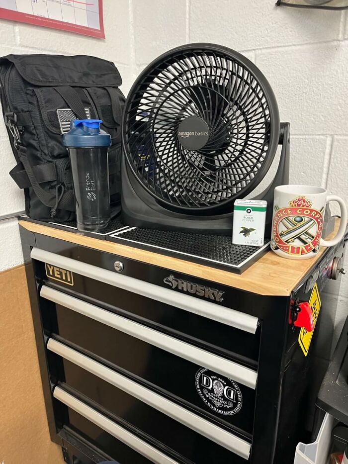 Amazon Basics fan on a tool chest with a black backpack and gym shaker bottle.