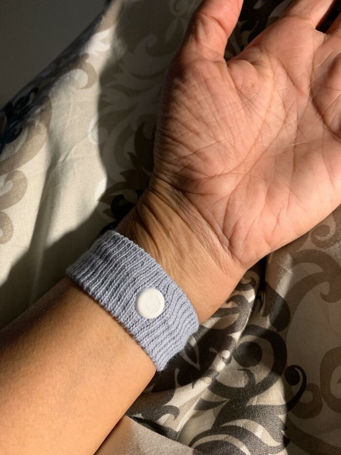Gray travel wristband on a person's wrist, useful for budget-friendly trips.