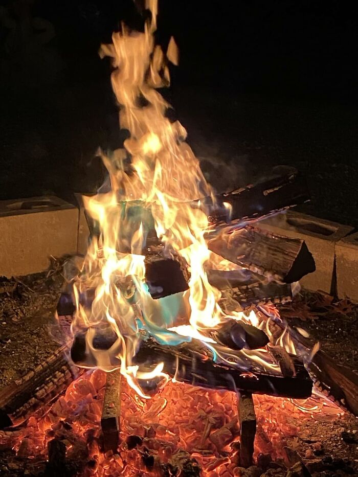 Trendsetting treasures: Vibrant campfire with dancing blue and orange flames illuminating the night.