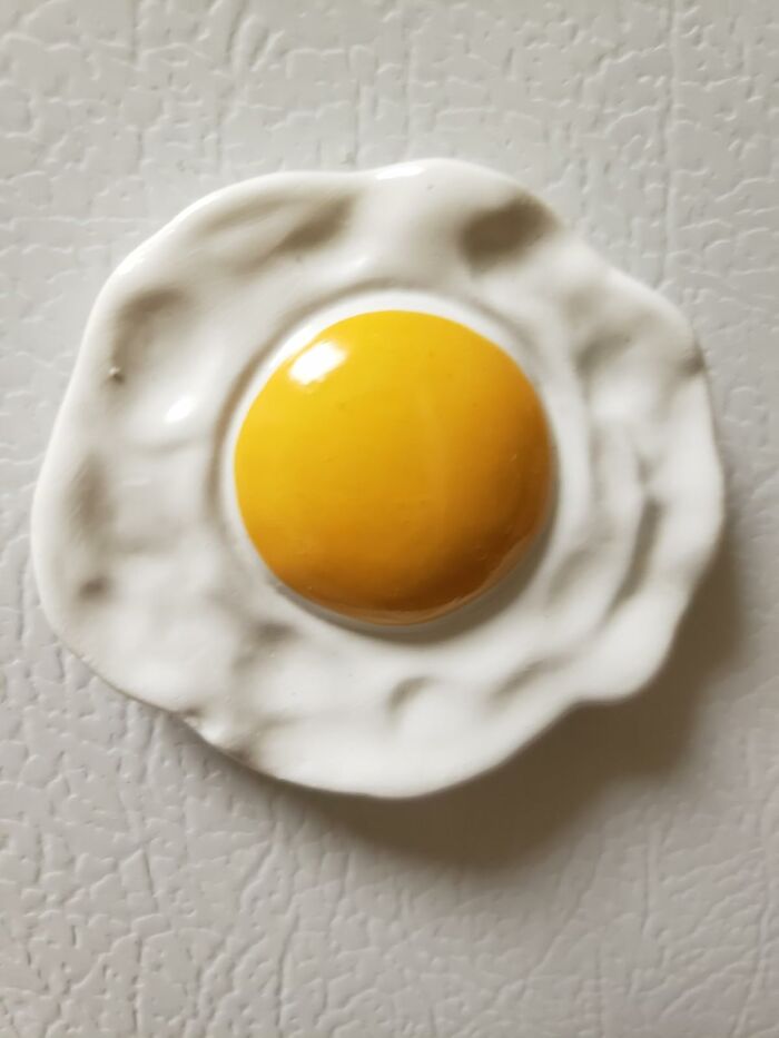 Food-shaped object resembling a fried egg with shiny yellow yolk and white textured edges on a light surface.
