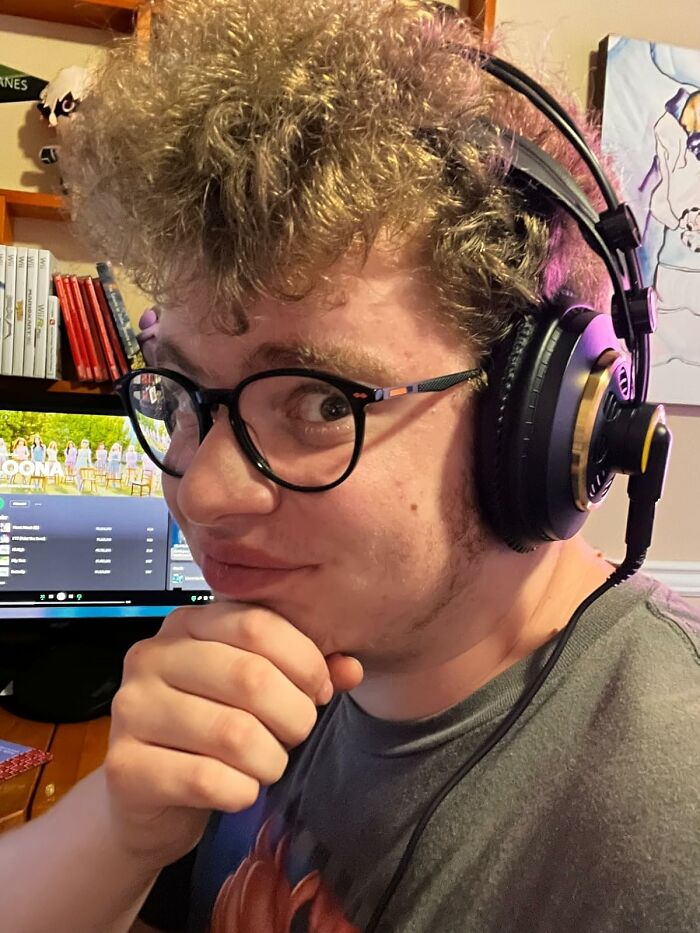 Person with curly hair wearing headphones and glasses, seated at a desk with a computer, representing lasting interests.
