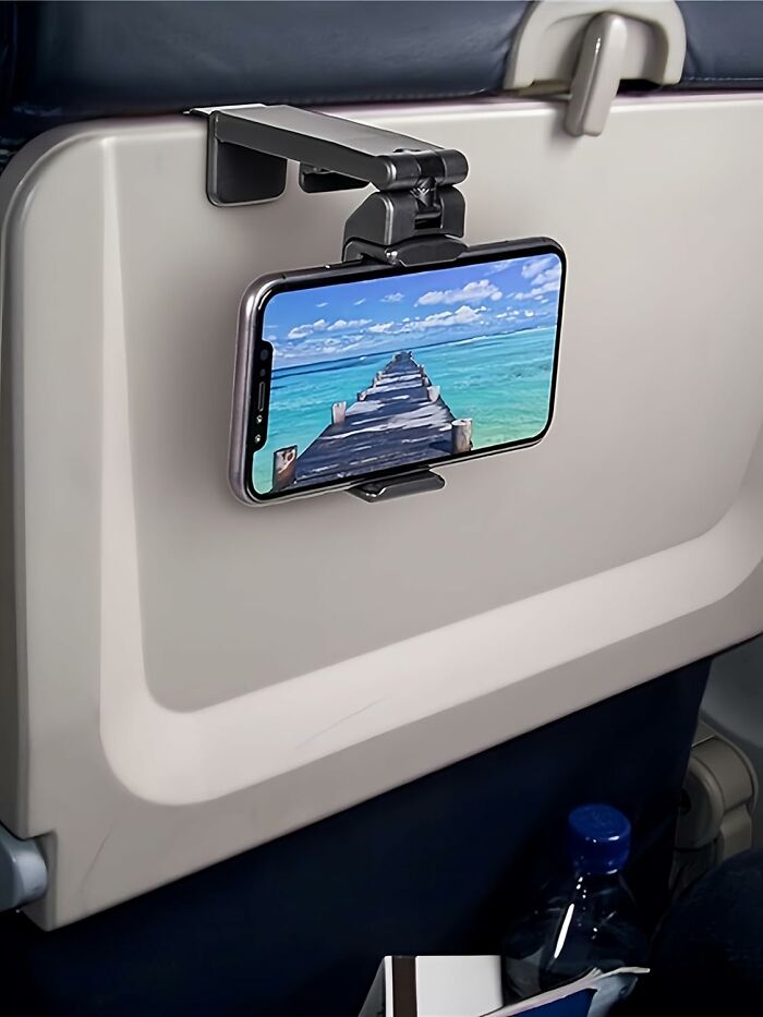 Phone holder attached to airplane tray table displaying a scenic pier, one of the popular Amazon haul finds.