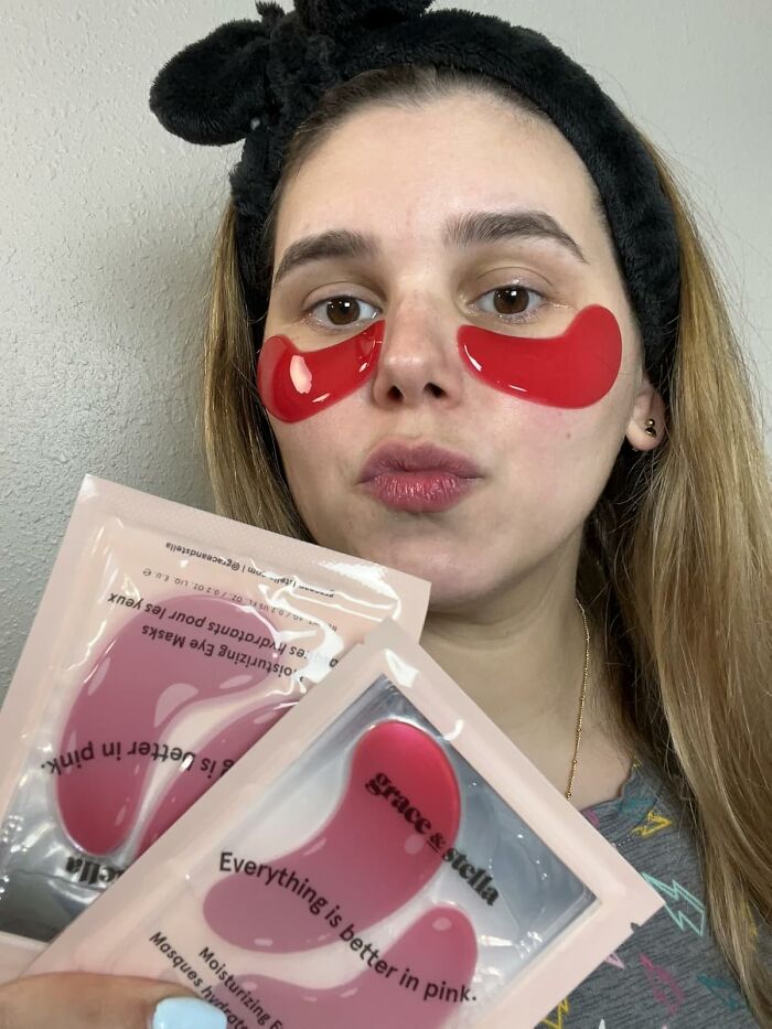 Woman wearing red moisturizing eye masks holding Grace & Stella beauty products, illustrating last minute Mother's Day gifts.