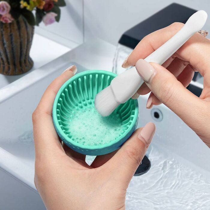 Hands holding a green silicone cleaning brush with soap foam, a top Amazon haul find for easy beauty tool cleaning.