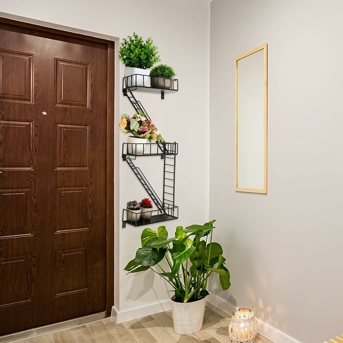 Stylish apartment entryway with plants, decorative shelves, and a large mirror for a welcoming ambiance.