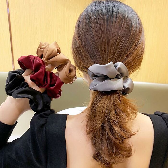 Woman wearing Amazon haul scrunchies in various colors, showcasing affordable shopping finds.