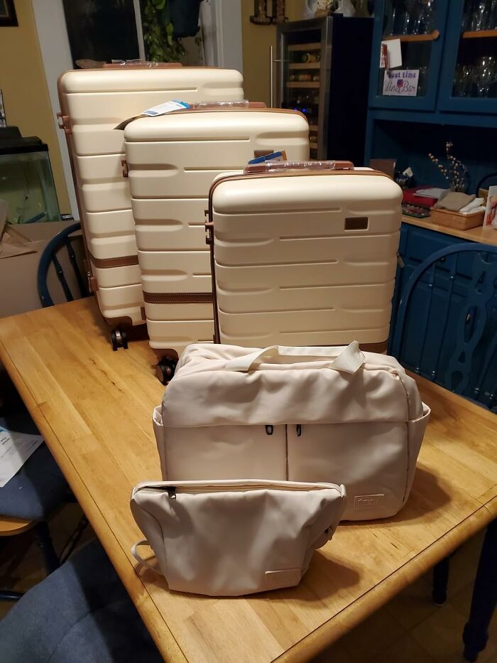 Set of beige luggage and travel bags arranged on a wooden table, ideal Mother's Day gifts for stylish travel.