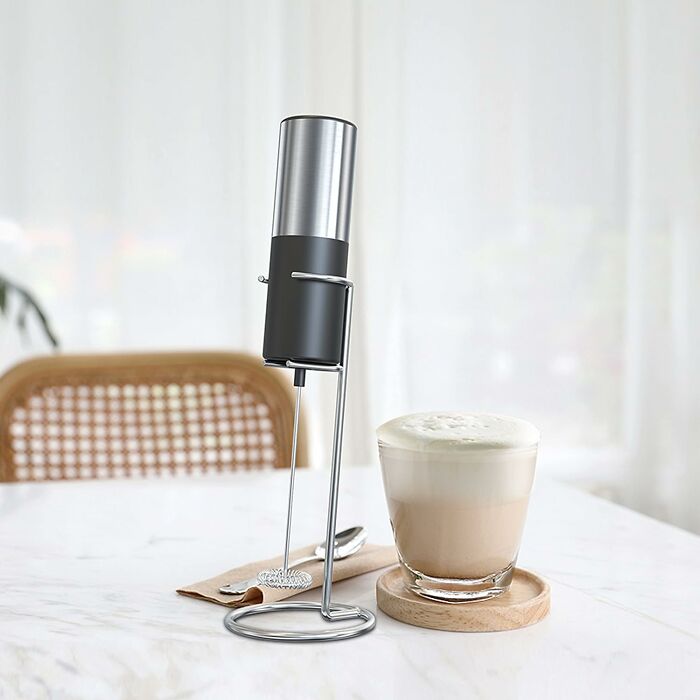 Handheld milk frother and frothy coffee on a wooden coaster, featured in popular Amazon haul finds.