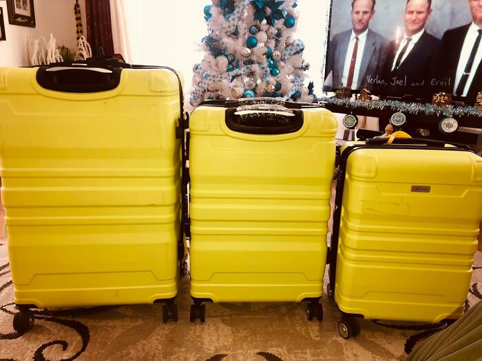 Yellow luggage set in a living room with a decorated Christmas tree in the background.
