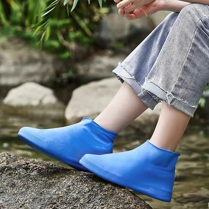 Person wearing blue waterproof shoe covers sitting by a stream, showcasing products from a shopping app.