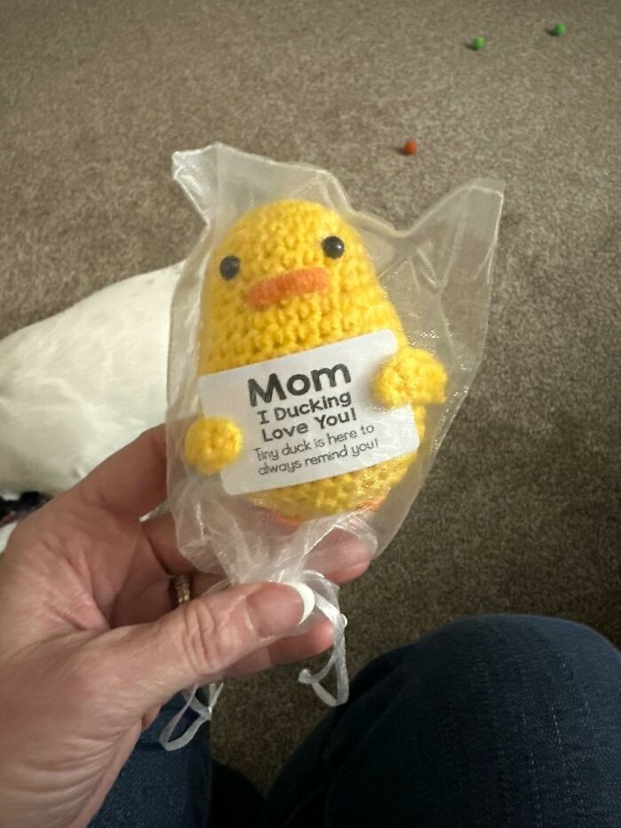 Hand holding a crocheted yellow duck gift with a love note, a creative Mother's Day gift idea alternative to socks.