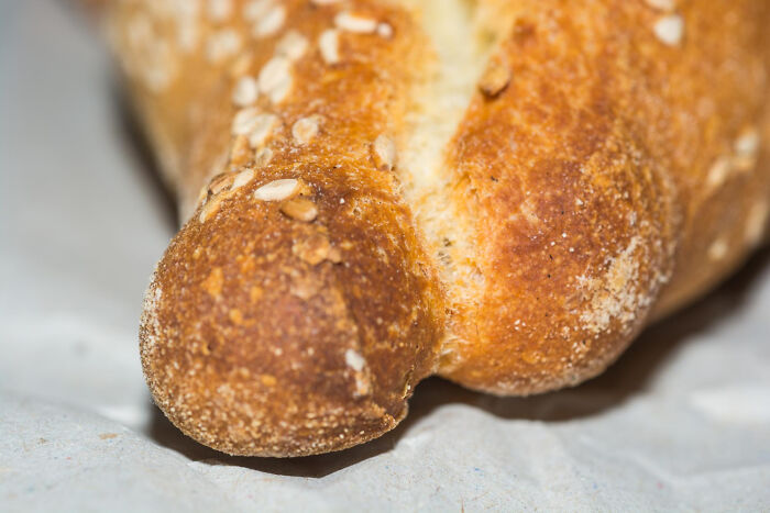 Close-up of a sesame-seed-coated bread resembling a duck's face, relating to bizarre house rules.