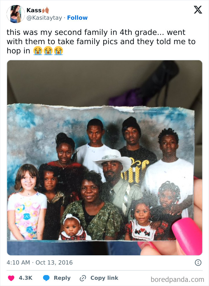 Hand holding a worn family photo featuring a diverse group of smiling people, capturing pure and uplifting moments.