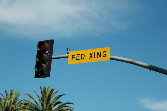 Traffic light with red signal and pedestrian crossing sign under a clear sky, illustrating obvious things noticed recently.
