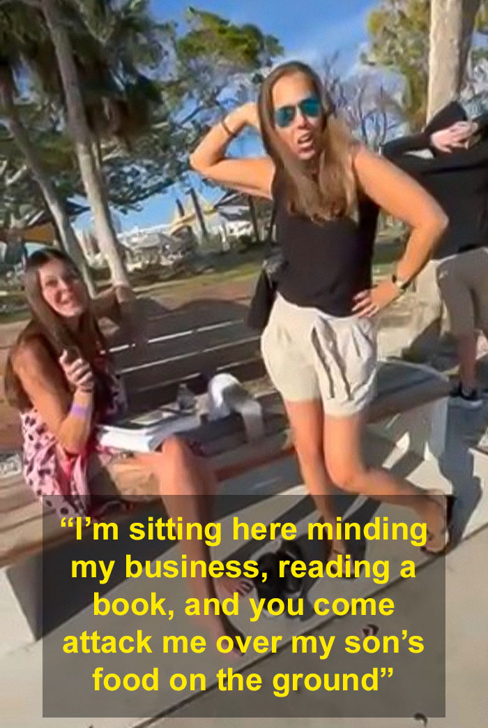 Women arguing at a park bench; one stands with hands on hips, the other sits, laughing.