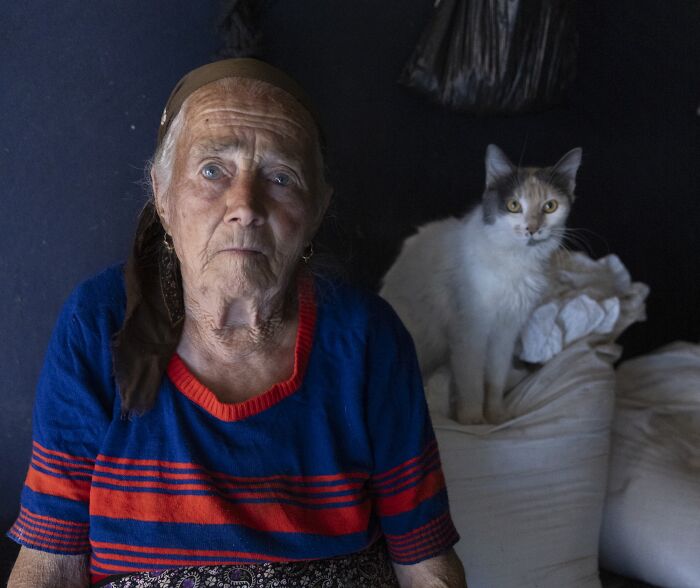 Elderly woman beside a cat, showcasing the vulnerability of aging in Michele Zousmer's powerful imagery.