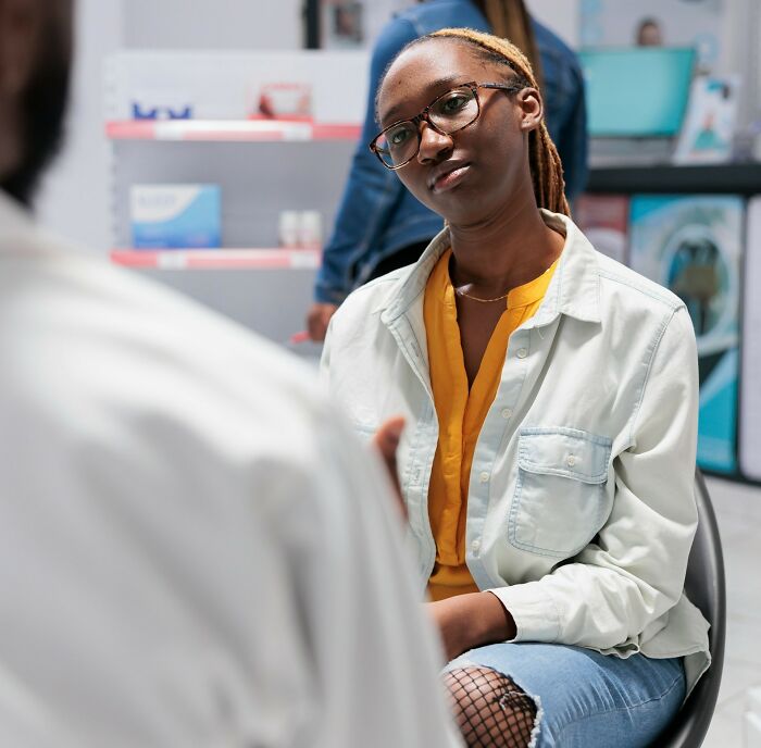 A woman listens attentively in a medical setting, highlighting disparities in prescribed pain meds for women.