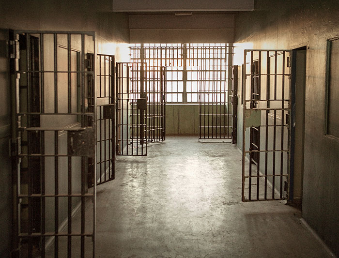 Prison hallway with open cell doors, focus on incarceration concept.