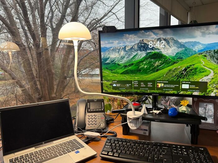 Work supplies on a desk with a monitor, laptop, phone, and lamp, enhancing a productive office environment.