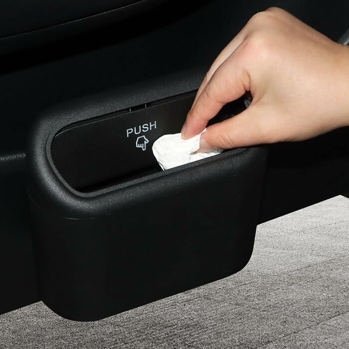 Hand pulling tissue from black portable trash bin in car, one of the Amazon haul finds trending for home and travel use.