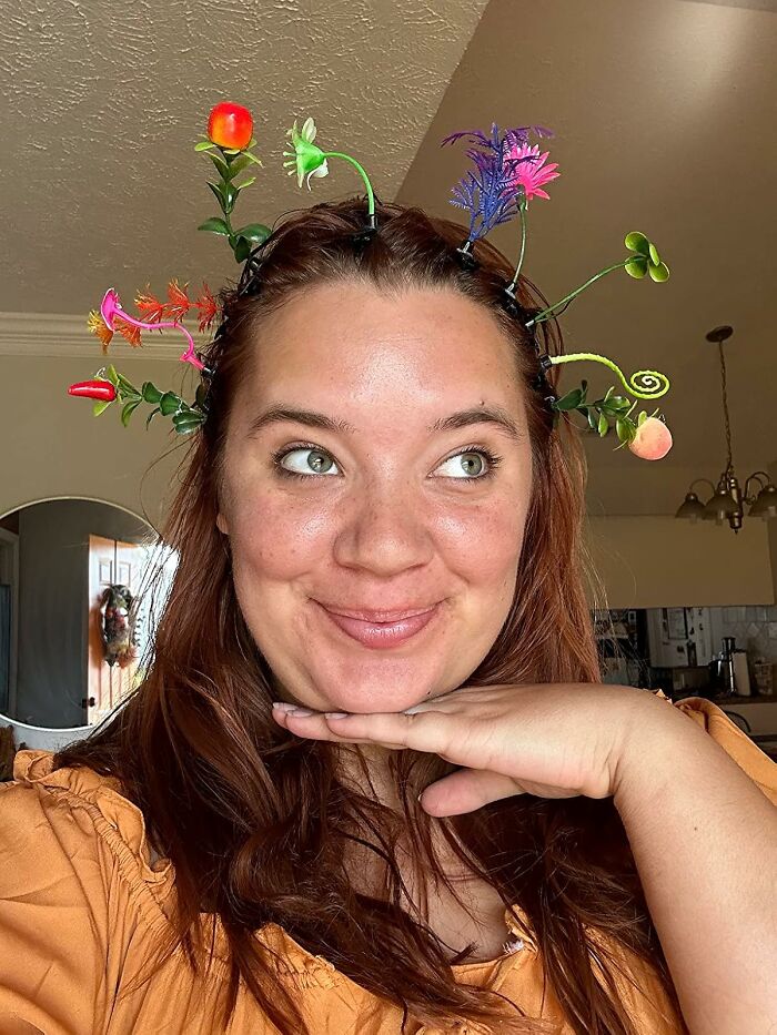 Woman wearing a colorful flower headband smiling indoors, showcasing items to unleash your inner child.