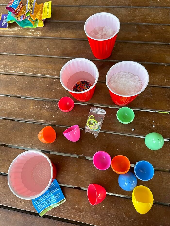 Colorful Easter treasures with plastic eggs and cups on a wooden table.