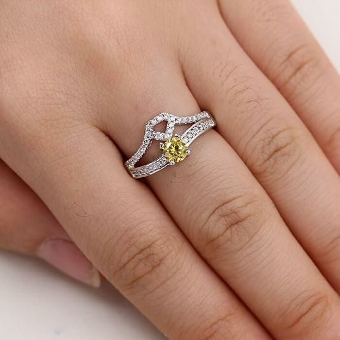A hand wearing an elegant silver ring with a yellow gemstone, showcasing a low-cost Amazon shopping find.